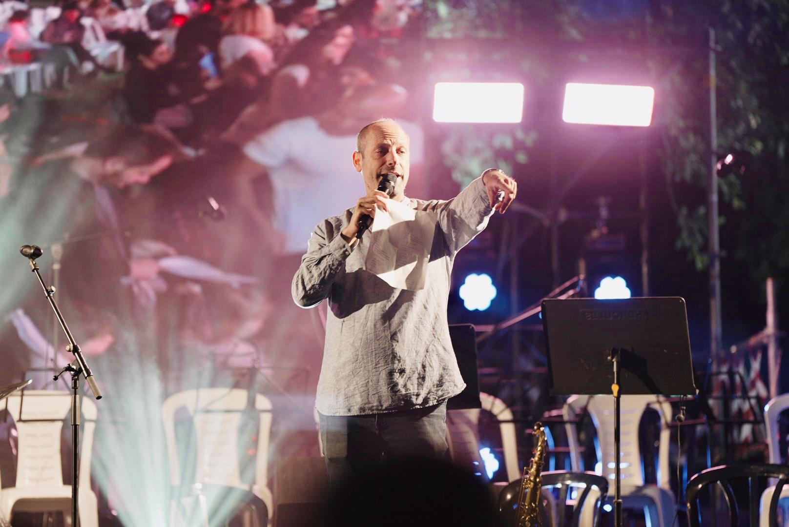 Itzik Weiss leading a singing event on stage